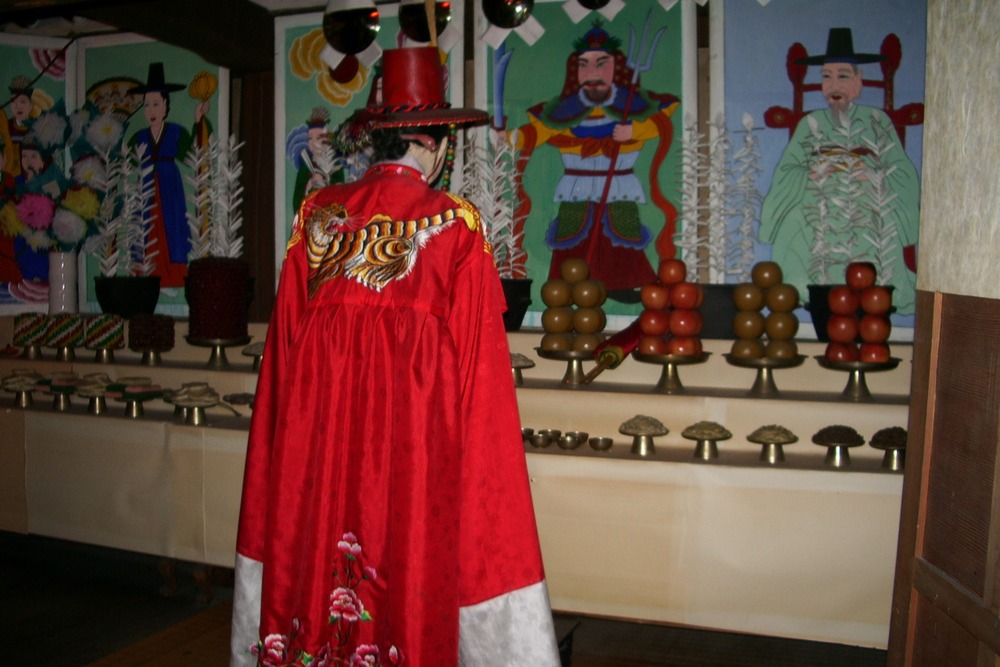 Korean mudang shaman in traditional red ceremonial costume at Lotte World Folk Museum